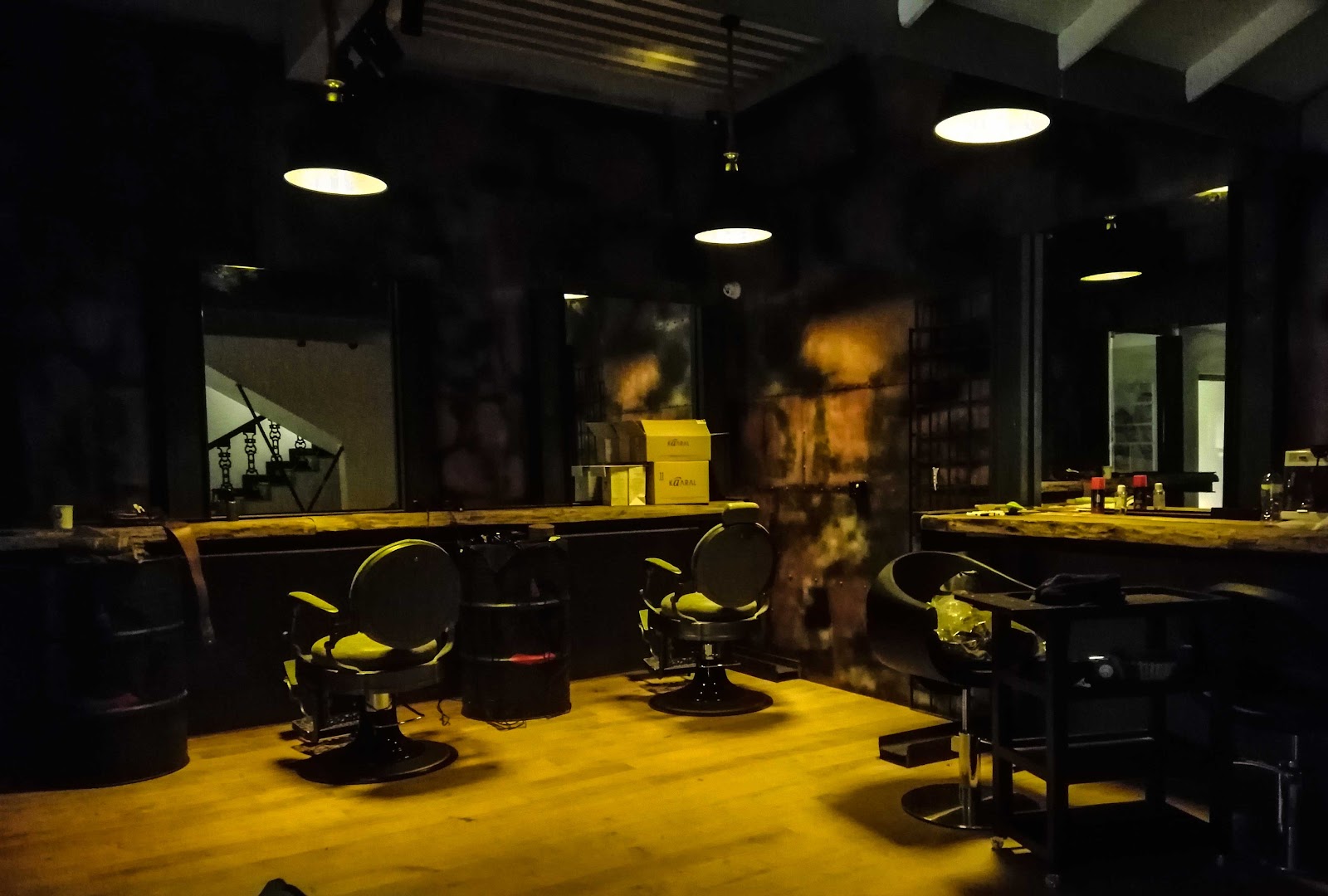 Dark styling room with mirrors, salon chairs, and amber pendant lights