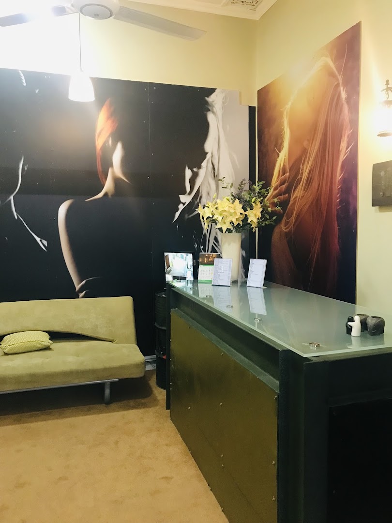 Warm salon reception with hair portrait murals, flowers, and a tan sofa